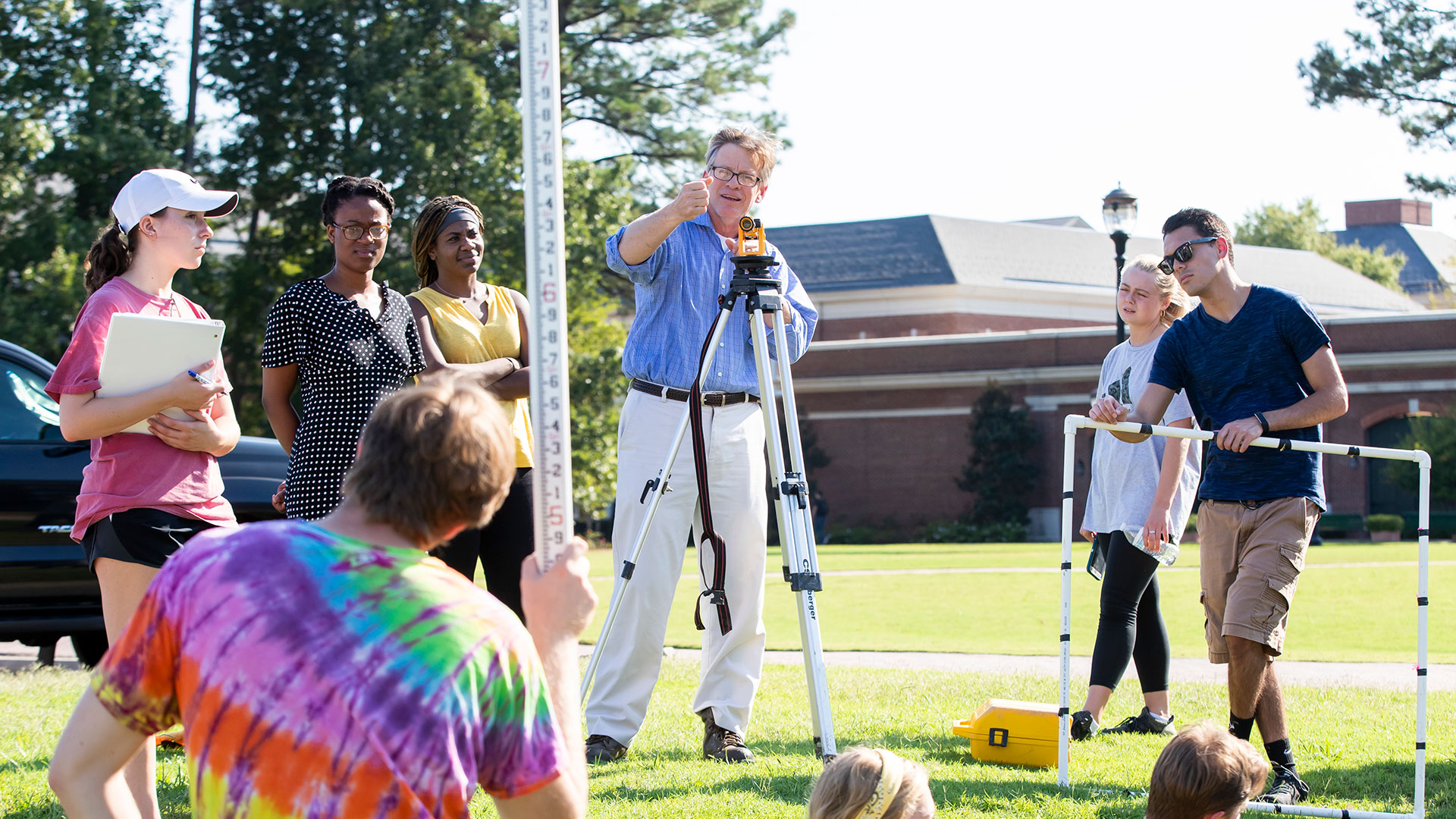 Professor conducting a class on surveying outside with students