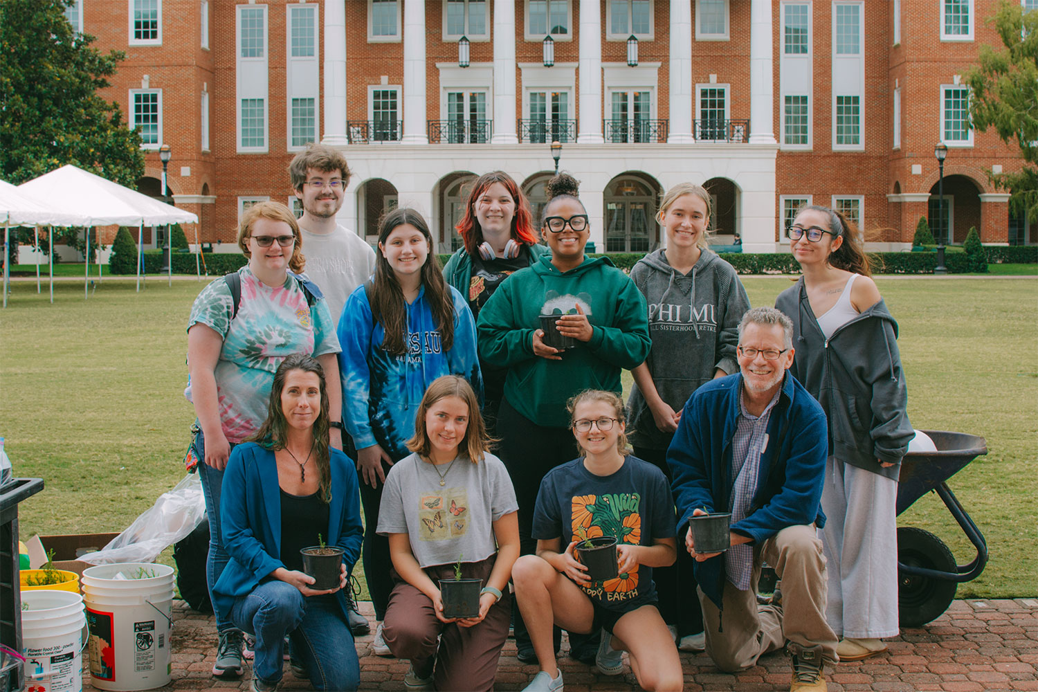 Christopher Newport's Fear 2 Hope members pose for a group photo, holding potted plants.