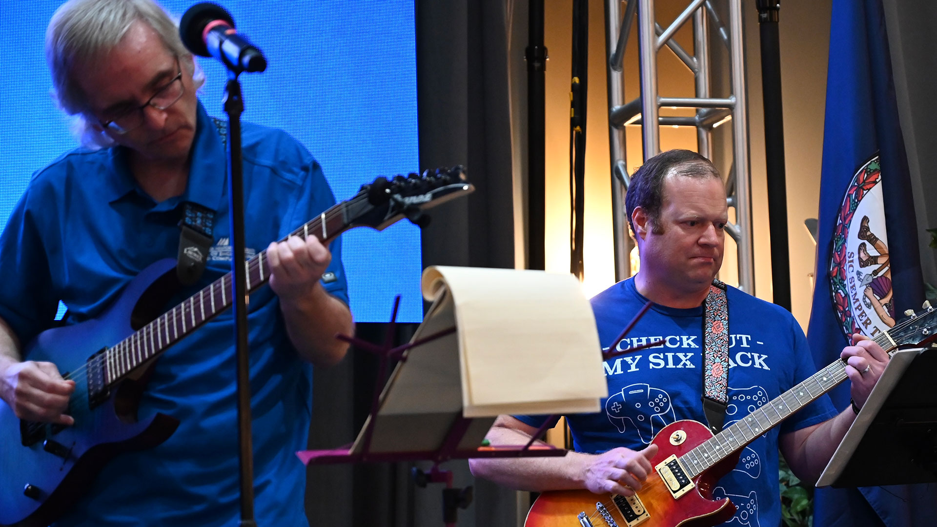 Two SEC professors play guitar on stage in front of microphones