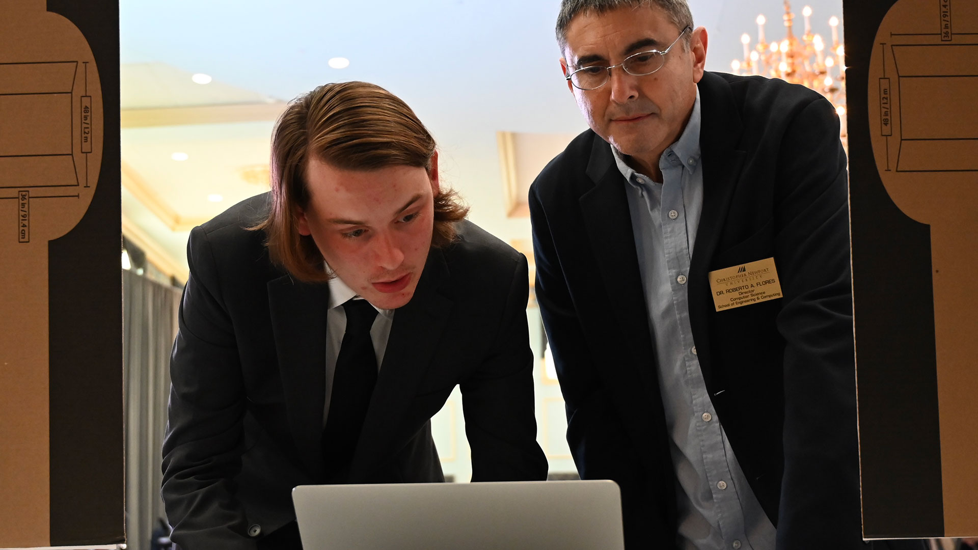 A student and professor look at a laptop screen