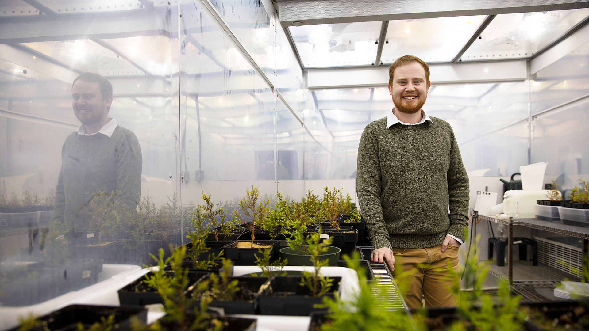 Biology major Patrick Wright in a greenhouse with plants