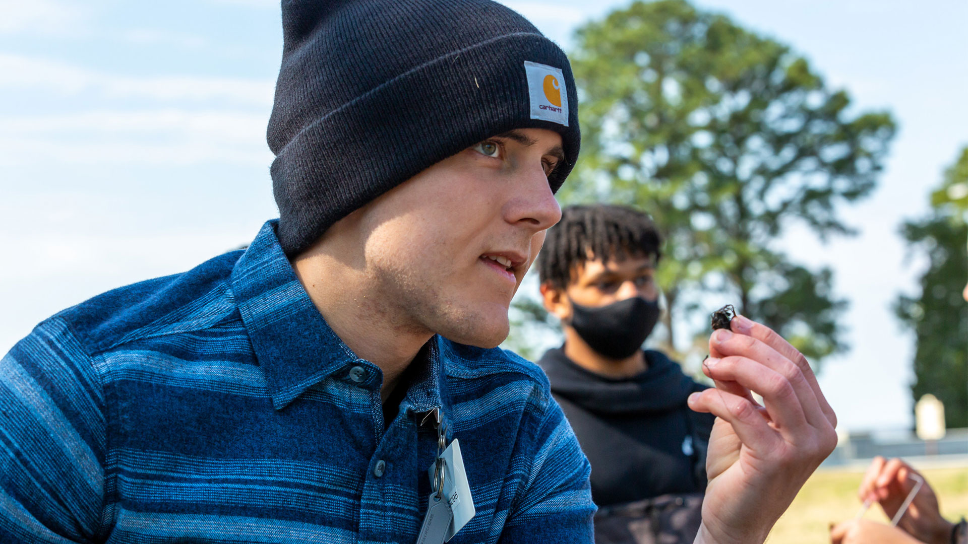 A Christopher Newport ecology student studies a specimen while engaged in outdoor environmental research.