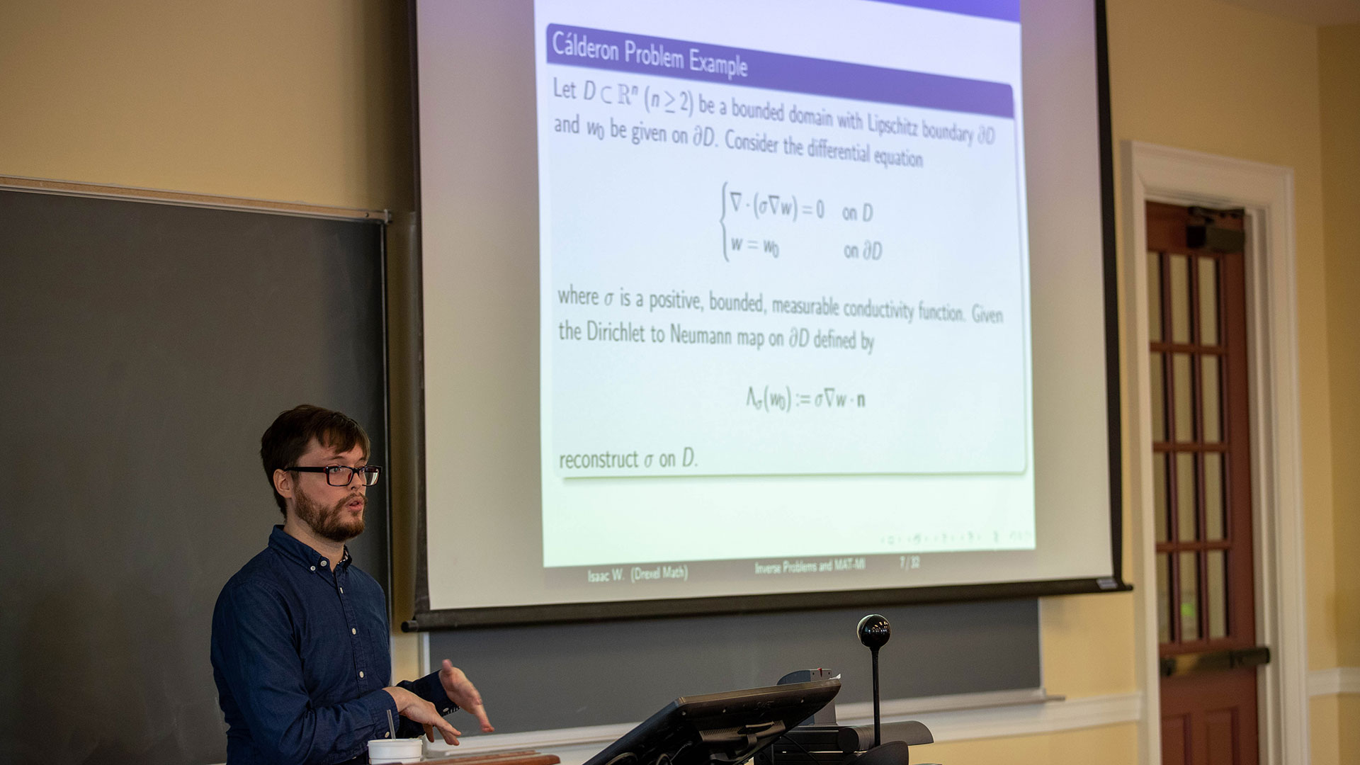 Math problem displayed on a projection screen and a lecturer explaining it at a math colloqium 