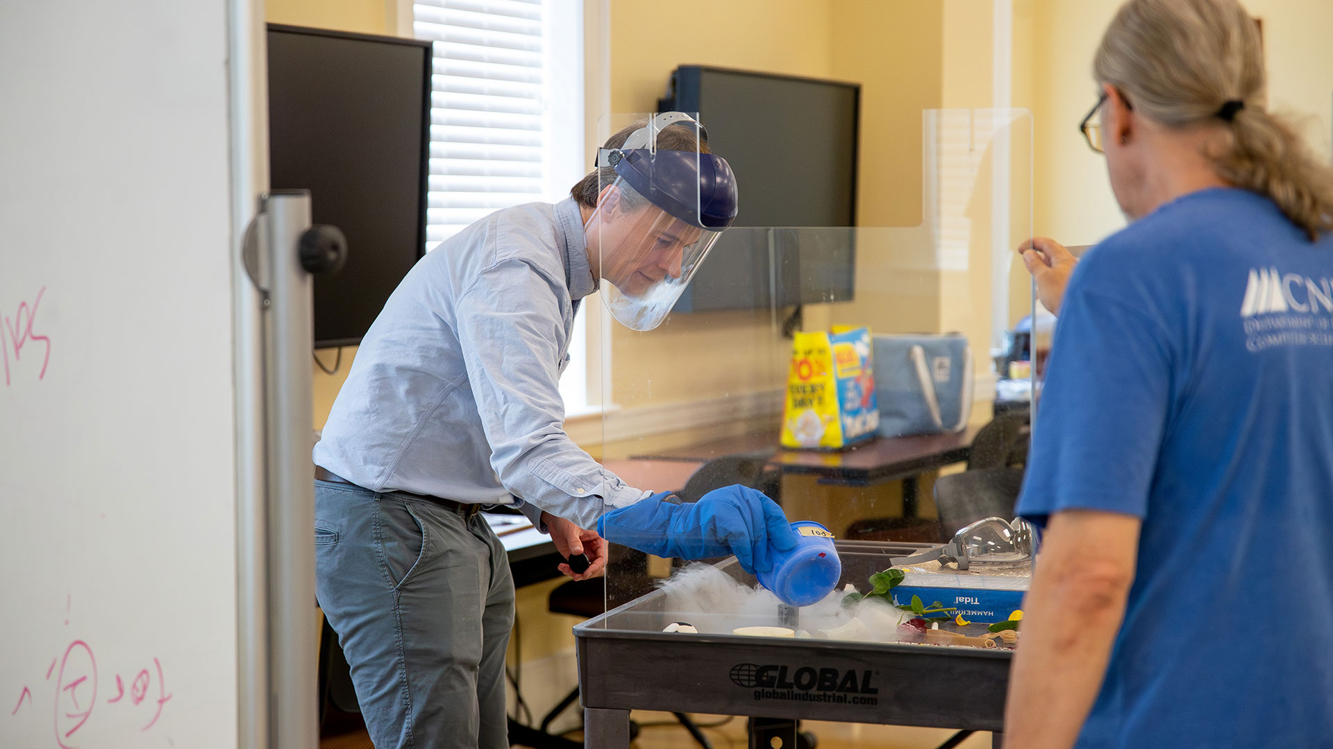 A professor wears protective gear while working with liquid nitrogen