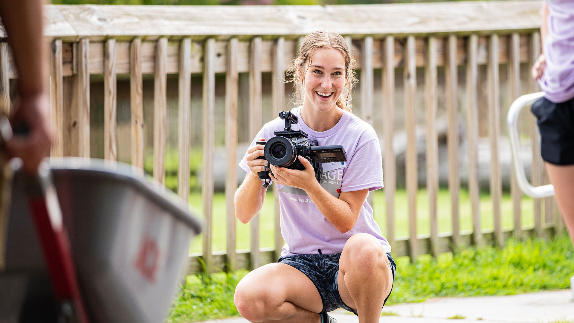 A girl with a digital film camera videos two other students helping out during Day One of Service