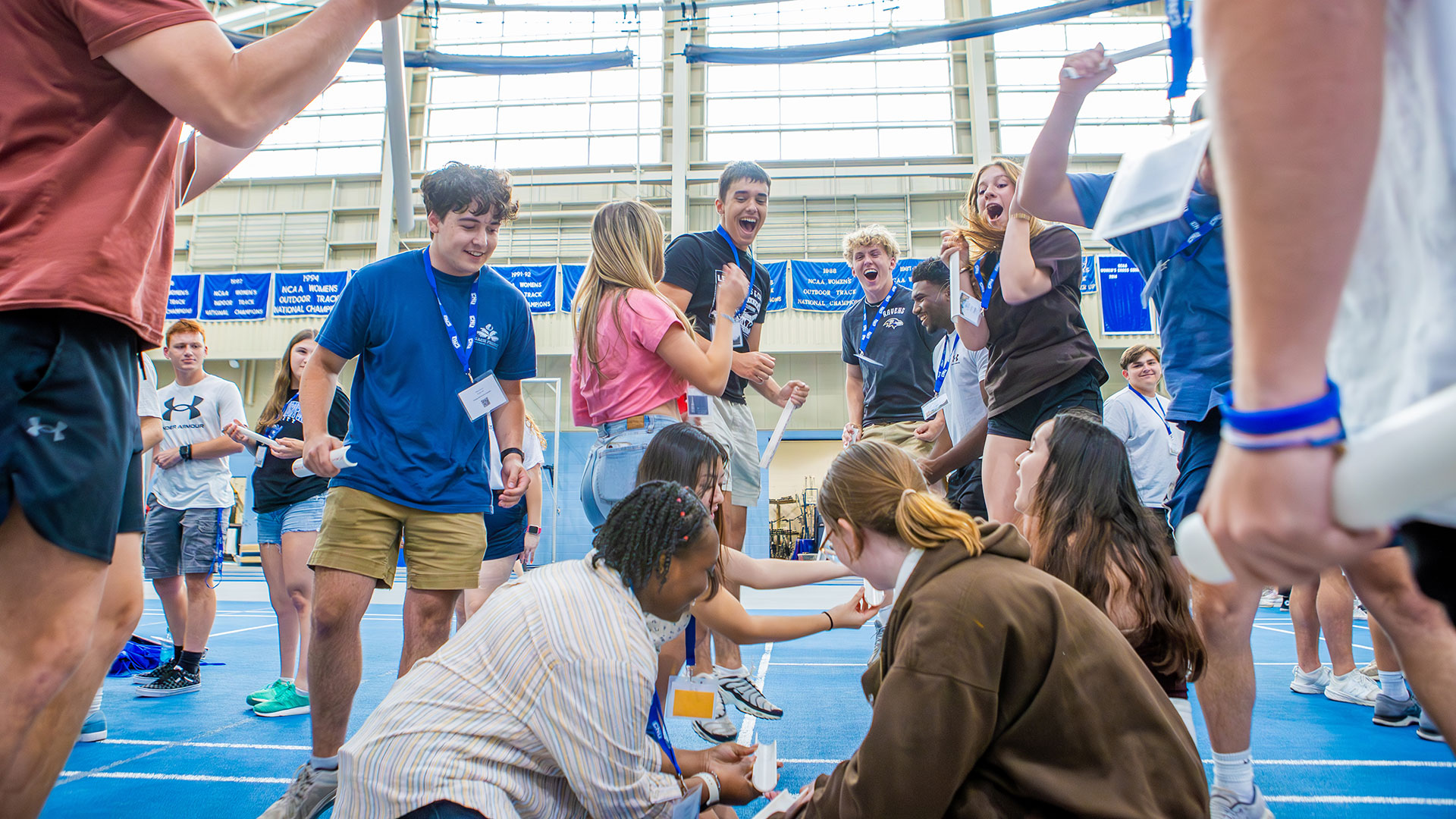 A group of students work together as a team with half-cut pvc pipe and cheer in celebration