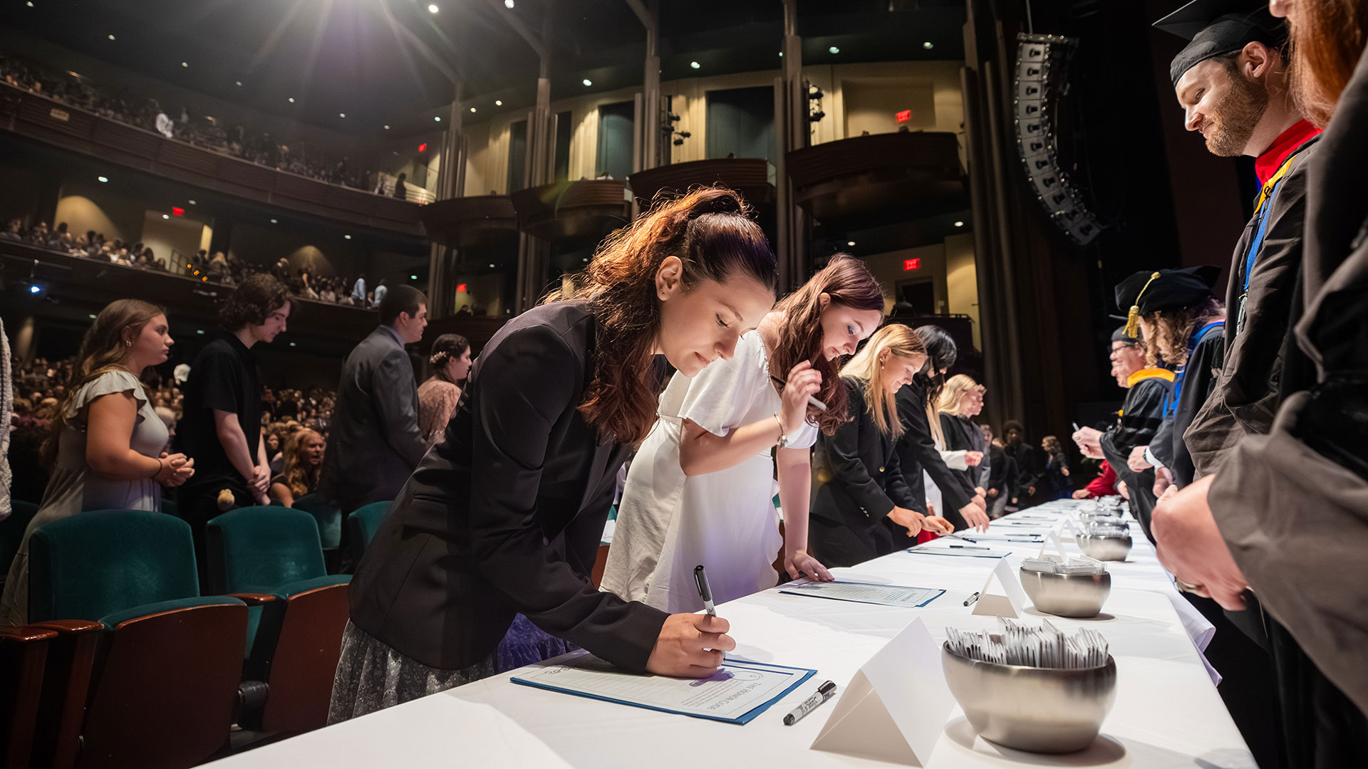 A student signs the Honor Code in front of faculty.