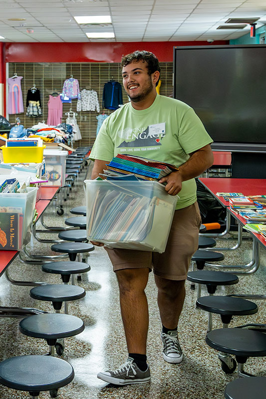 Student carrying books at an elementary school during Day One of Service